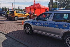 radiowóz stoi przed punktem kontroli pojazdów, w oddali policjanci rozmawiają z kierowcami