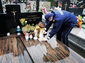 Umundurowany komendant Policji zapala znicze na grobach i modlli się