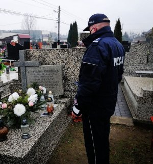 Umundurowany komendant Policji zapala znicze na grobach i modlli się