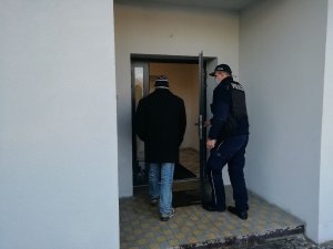 Umundurowany policjant wchodzi z mężczyzną do urzędu