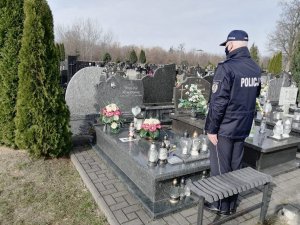 Umundurowany policjant stoi przy grobach zmarłych