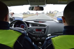 policjanci w żółtych kamizelkach jadą radiowozem po drodze