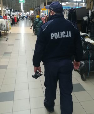 umundurowany policjant odwrócony tyłem idzie korytarzem sklepu