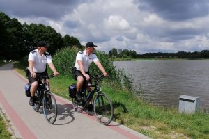 umundurowani policjanci jadą rowerami wzdłuż jeziora