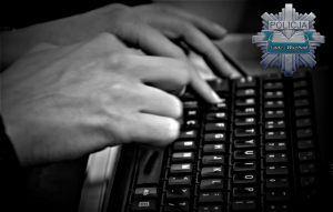 dłonie piszące na klawiaturze od komputera, w prawym górnym rogu policyjna gwiazda koloru szarego z zielonym paskiem KPP Łódż Wschód