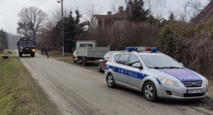 radiowozy policyjne i wóz saperski stoją na drodze gdzie w pobliżu zabezpieczony jest niewybuch
