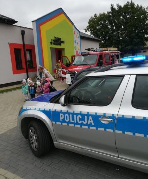 dzieci stoją przy radiowozie policyjnym