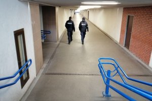 dwóch umundurowanych policjantów patroluje korytarz dworca kolejowego