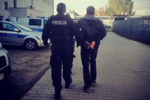 umundurowani policjanci prowadzą zatrzymanego mężczyznę
