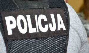 plecy policjanta w czarnej kamizelce z napisem policja na plecach