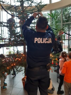 policjant dekoruje z dziećmi choinkę