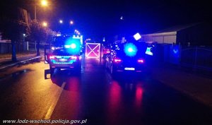 dwa radiowozy oznakowany i nieoznakowany na włączonych niebieskich sygnałach stoją przy miejscu wypadku drogowego , przed nimi stoi wóz strażacki