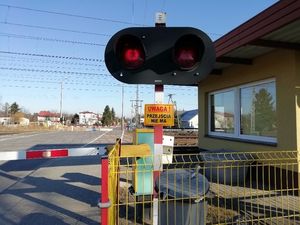 opuszczone rogatki przy przejeździe kolejowym i migający sygnalizator na czerwono