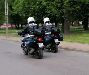 dwóch policjantów na policyjnych motocyklach jedzie obok siebie drogą