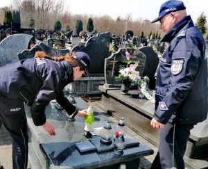 policjanci stoją przy grobach na cmentarzu