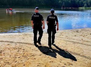 Policjantka z policjantem idą plażą w kierunku wody