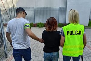 policjanci prowadzą zatrzymaną kobietę