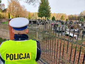 policjanci w białych czapkach na głowie i żółtych kamizelkach z napisem policja stoją przed cmentarzem