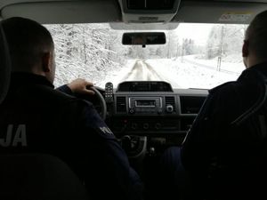dwóch policjantów jedzie radiowozem po zaśnieżonej drodze
