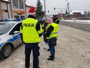 Dwóch policjantów przekazuje kobietom kamizelki odblaskowe.