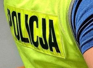 Policjant w żółtej kamizelce z napisem policja na plecach.