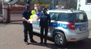 Policjanci dostarczają tort urodzinowy dla dziewczynki przebywającej na kwarantannie.