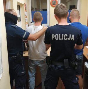 Policjanci prowadzą zatrzymanego mężczyznę.