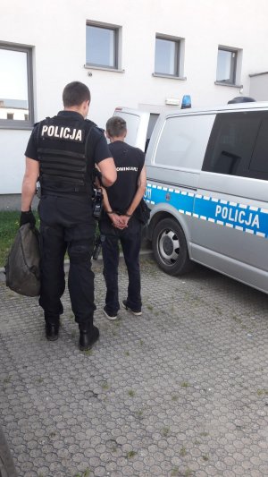 Funkcjonariusz prowadzi sprawcę włamań.