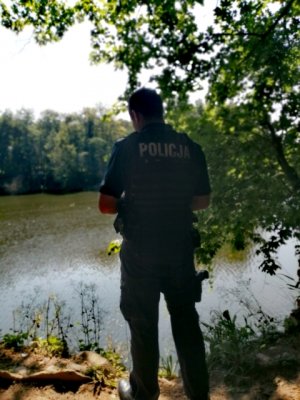 Funkcjonariusz patroluje teren przy zbiorniku wodnym.