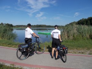 Policjanci na rowerach patrolują zbiornik wodny.