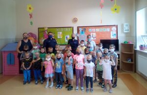 Policjanci stoją z przedszkolakami i opiekunami.