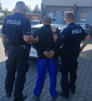 Policjanci prowadzą zatrzymanego mężczyznę.