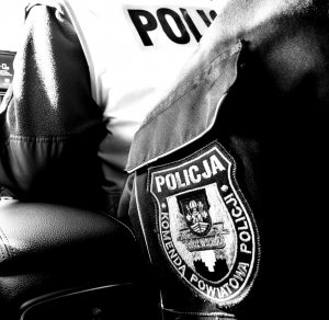 policjant siedzi w radiowozie, widoczna naszywka na mundurze