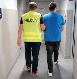 korytarz komendy, policjant prowadzi zatrzymanego mężczyznę