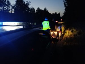 Dzielnicowy rozdaje kamizelki odblaskowe mieszkańcom.