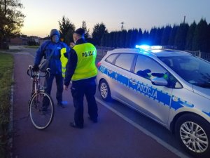 Dzielnicowy rozdaje kamizelki odblaskowe mieszkańcom.