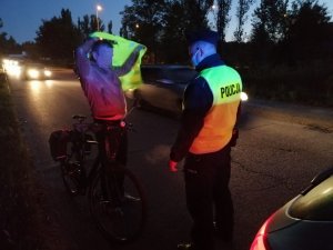 Dzielnicowy rozdaje kamizelki odblaskowe mieszkańcom.