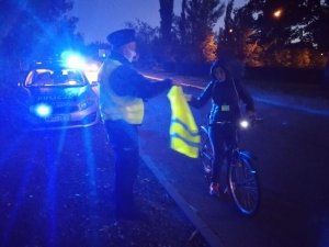 Dzielnicowy rozdaje kamizelki odblaskowe mieszkańcom.