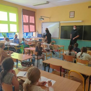 Policjanci mówią do dzieci, które siedzą w ławkach o bezpieczeństwie.