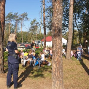 Policjanci mówią do dzieci, które siedzą w ławkach o bezpieczeństwie.