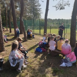 Policjanci mówią do dzieci, które siedzą w ławkach o bezpieczeństwie.