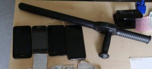 telefony, leki i tonfa znalezione przy zatrzymanych leżą na blacie biurka
