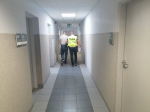 Policjant prowadzi zatrzymanego mężczyznę.