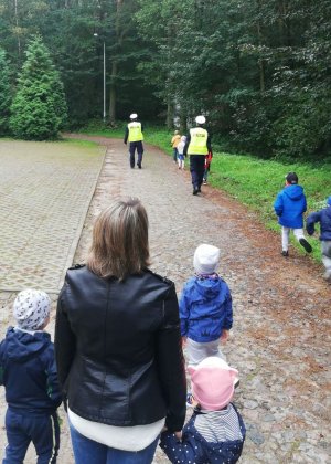 Policjanci pokazują przedszkolakom jak właściwie zachowywać się na drodze i przez nią przechodzić.