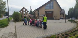 Policjanci przechodzą z dziećmi przez jezdnię na przejściu dla pieszych.