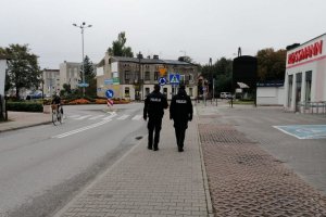 Policjant i policjantka umundurowani patrolują idąc pieszo ulicami, skwerami i peronami dworca kolejowego czy wszyscy przestrzegają obostrzeń.