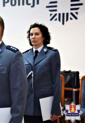 Policjantka w mundurze galowym stoi na baczność, w lewej dłoni trzyma dokument