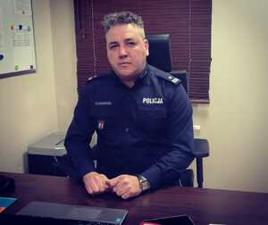 Umundurowany komendant siedzi za biurkiem.