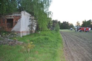 Stojący w lesie budynek, z zawalonym dachem, obok miejsca stoją strażacy i służby ratunkowe.
