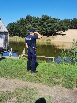 Policjant umundurowany stoi nad wodą i obserwuje